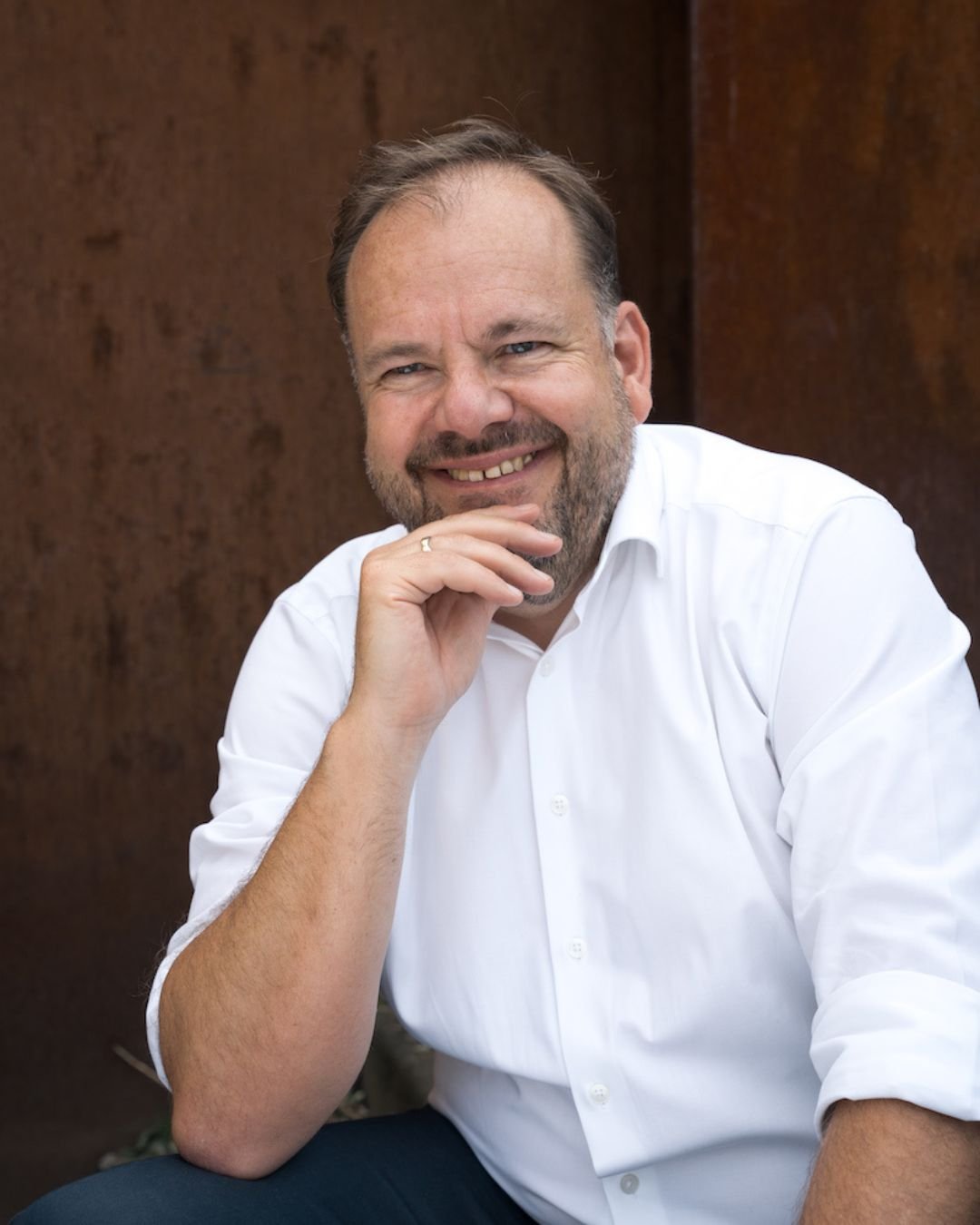 Eine lächelnde Frau mit dunklen, langen Haaren und Brille. Sie lächelt in die Kamera und scheint sich den Betrachter:innen zuzuwenden.